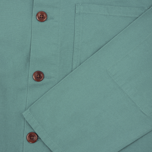 A close up of a dusty blue shirt with three brown front buttons.